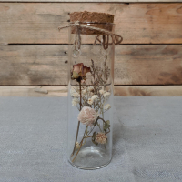 een met droogbloemen gevuld glazen buisje